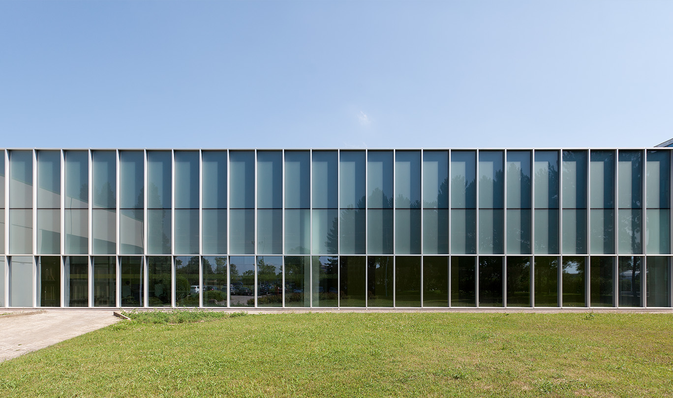 Un grande edificio di vetro con un'area verde circostante