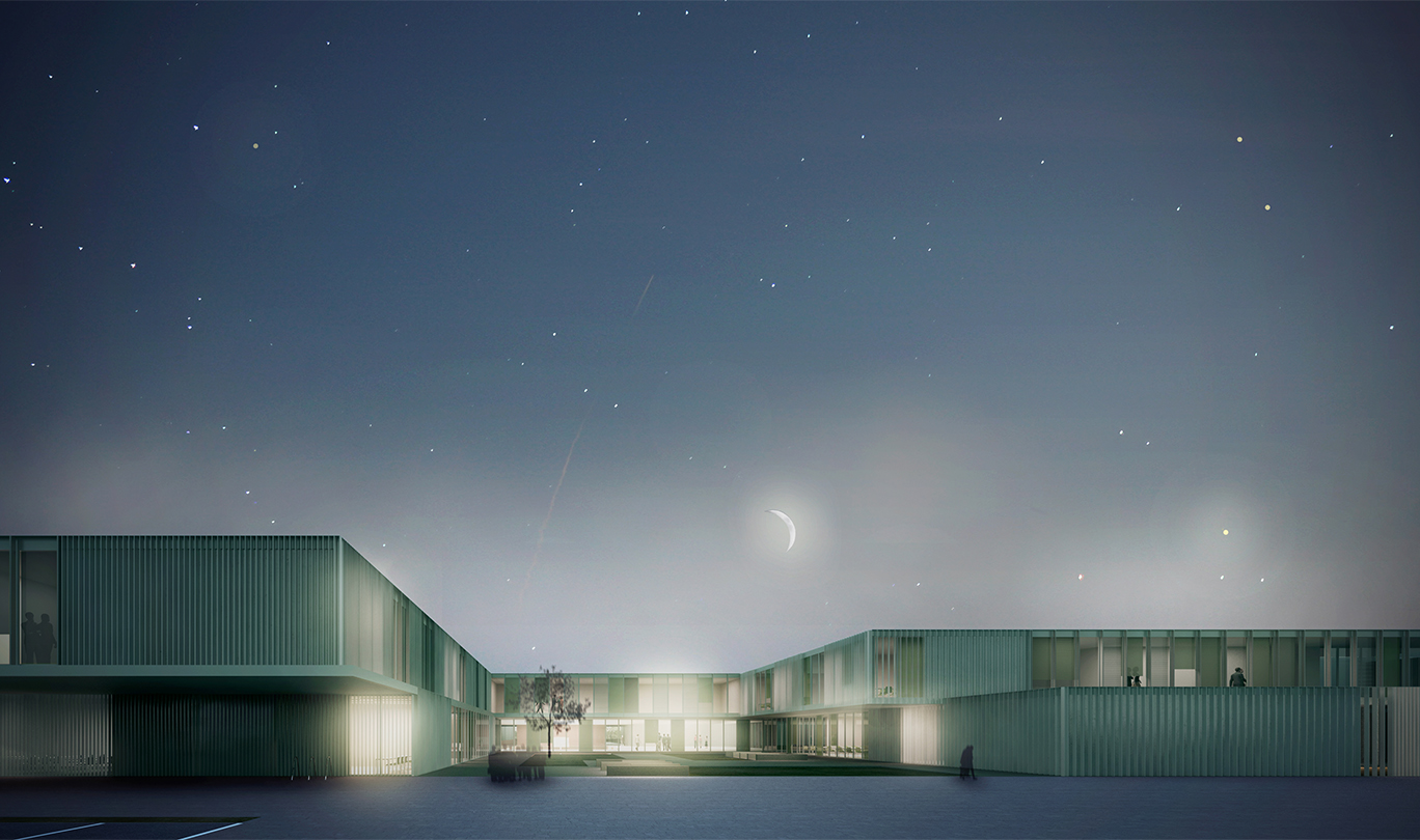Vista notturna dell'edificio scolastico illuminato, che lascia intravedere l'articolazione dei diversi volumi