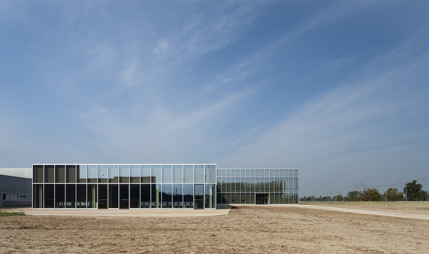 Volumi edificio con facciate vetrate che si stagliano sullo sfondo di un paesaggio rurale