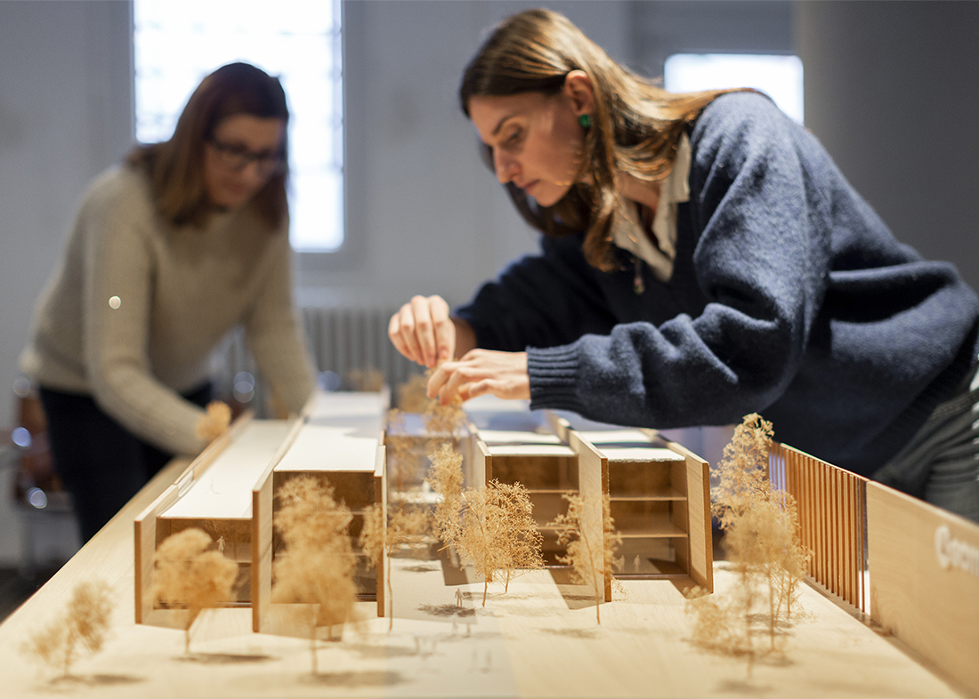 Due persone lavorano su un plastico architettonico di un edificio moderno con alberi in miniatura